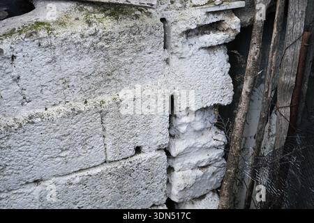 Close-up of a weathered, whitewashed stone wall with rough texture and moss, traditional rural Cretan architecture details from Rotasi village. Stock Photo