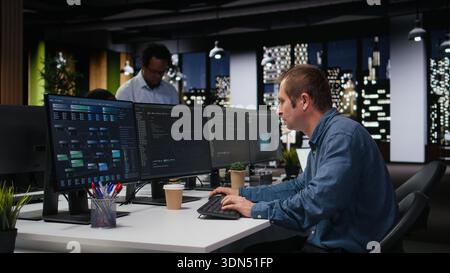 Programmer typing complex code on computer, developing machine learning models to automate business tasks in workspace. Developer writing programming language scripts on PC Stock Photo