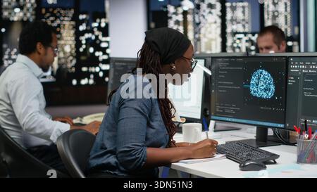 Programmer taking notes at desk in Silicon Valley company office, developing apps. IT expert using machine learning to do coding, writing on notepad, debugging applications to resolve issues Stock Photo