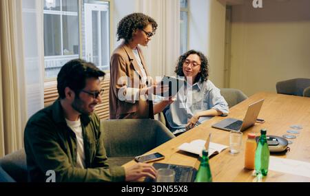 Team Members Engaging In Detailed Review And Planning Session With Scattered Notes And Open Laptops Stock Photo