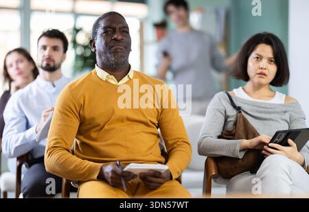 Portrait of an attentive man in linguistics class, taking notes in notebook Stock Photo