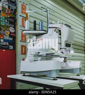 Balikpapan, Indonesia - November 22, 2025. Computerized Brother embroidery machine with LCD touchscreen display in a commercial storefront. Stock Photo
