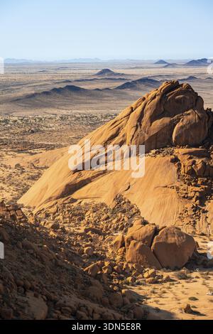 Massive rocks rise in the endless expanse of desert against a clear sky, Spitzkoppe, Namibia Stock Photo