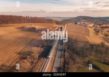 Wide landscape with railroad tracks and a distant train, surrounded by fields and forests, fire drill on the Hermann Hesse Railway, Ostelsheim, German Stock Photo