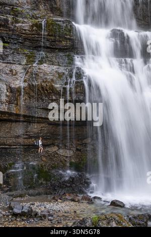 Little hiker in front of large Cascata di Mezzo waterfall, long exposure, Vallesinella, Brenta, Trentino, Italy Stock Photo