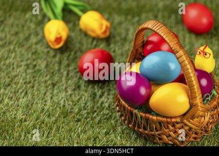 Colourful easter eggs in a basket in a meadow surrounded by flowers Stock Photo