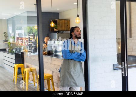 Diverse coworkers crossing arms and operating espresso machine at cafe with OPEN sign, copy space Stock Photo