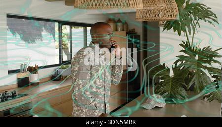 Talking man wearing grey camouflage jacket holding smartphone to ear in kitchen with camouflage cap Stock Photo