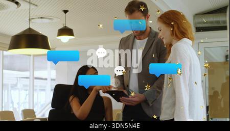 Three colleagues wearing office attire reviewing tablet in open-plan office with blue chat overlays Stock Photo