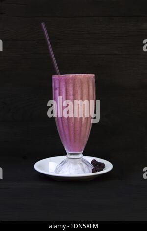 Glass with blueberry smoothie and milk isolated on black background Stock Photo