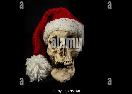 Human skull with christmas ornaments and elf hat isolated on black background Stock Photo
