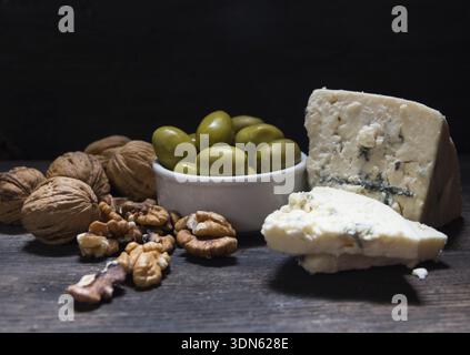 Roquefort cheese with walnuts and olives on dark background Stock Photo