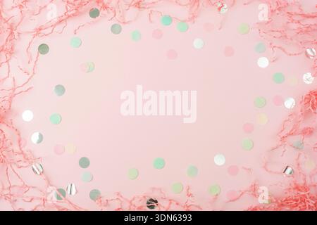 Frame made of colorful confetti and shredded paper on pink background. Holiday party concept. Top view, flat lay. Stock Photo