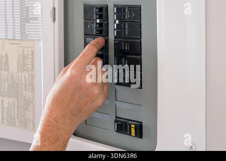 Woman's hand operating a residential electrical panel inside a home. Concept of household electricity, power control, safety, maintenance, and home ut Stock Photo