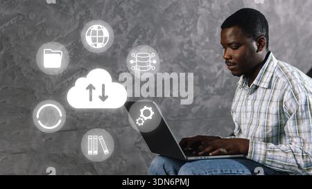 Man uses laptop to access cloud services while seated indoors during the daytime Stock Photo