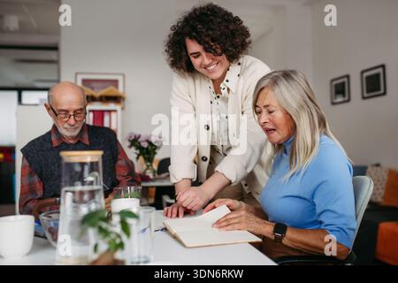 Female volunteer spending time with seniors in community center. Stock Photo