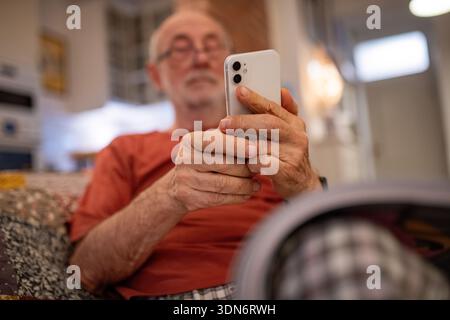 Elderly man holding and using a smartphone. Stock Photo