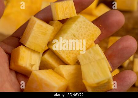 closeup orange pumpkin cut into pieces on a wooden chopping board, ripe and sweet pumpkin for baking in the kitchen Stock Photo