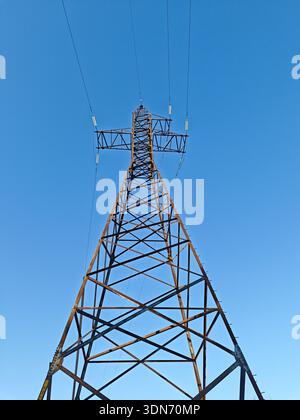 High voltage power line pylon tower against a clear blue sky Stock Photo