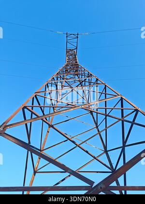 Low angle view of a tall metal electricity pylon against a clear blue sky Stock Photo