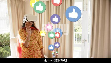 Pointing Indian woman wearing VR headset, yellow kurta, red dupatta, touching like icons at home Stock Photo