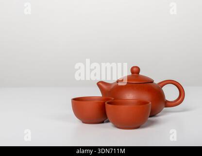 ceramic teapot with two small bowl cups arranged on table. Warm terracotta color and rounded forms create a calm teatime composition Stock Photo