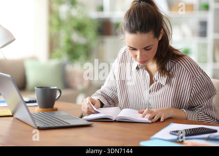 Serious tele worker consulting paper agenda working at home Stock Photo