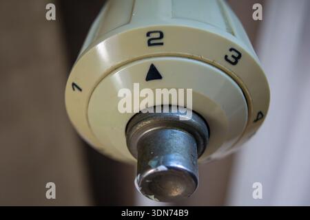 Close-up view of a mechanical thermostat dial with numbered scale and indicator arrow. Stock Photo