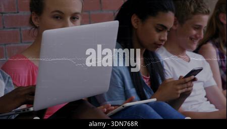 Sitting students in casual clothes using laptop and devices by red brick wall with waveform overlay Stock Photo