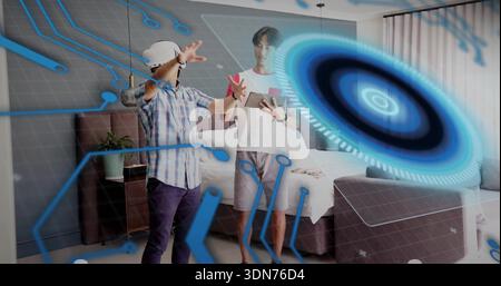 Reaching adult in plaid shirt and teen with tablet using hologram in bedroom, VR headset Stock Photo
