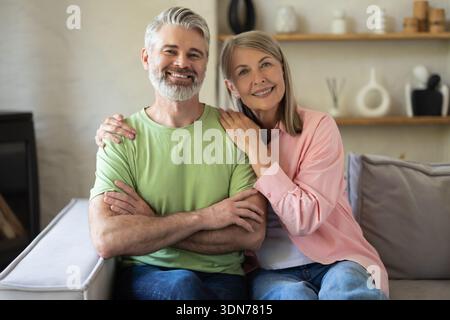 Smiling senior couple posing for portrait while sitting on sofa Stock Photo