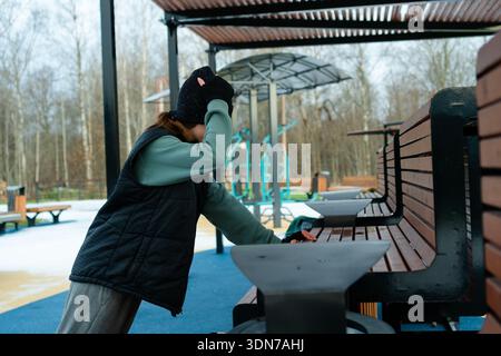 A woman doing push-ups and adjusting her hat during her outdoor workout routine. Emphasizing the importance of upper body exercises and comfort. Stock Photo