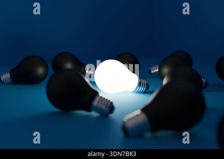 Glowing light bulb surrounded by many black bulbs on a deep blue background. Concept of a unique bright idea, standing out from the crowd, individuali Stock Photo