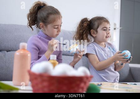 Two sisters decorating Easter eggs at home Stock Photo