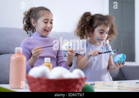 Two sisters decorating Easter eggs at home Stock Photo
