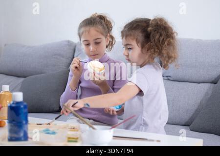 Two sisters decorating Easter eggs at home Stock Photo