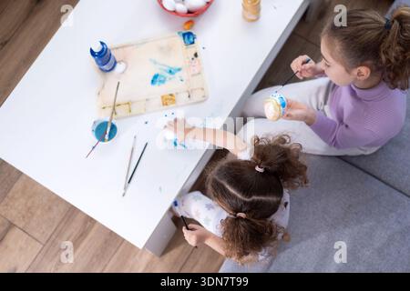 Two sisters decorating Easter eggs at home Stock Photo