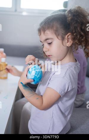 Two sisters decorating Easter eggs at home Stock Photo