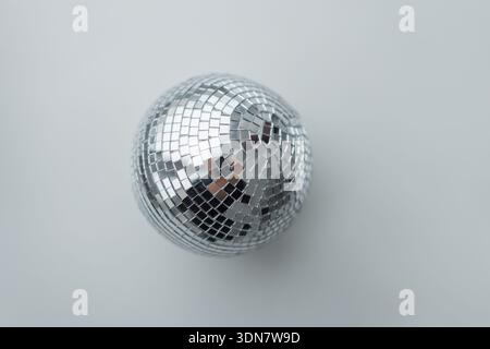 minimalist top-down shot of a silver disco ball centered on a light grey background. This high-quality image highlights reflective mirror tiles, perfe Stock Photo