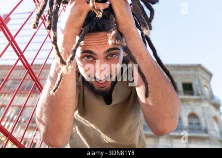Young man with dreadlocks touching his hair, expressing freedom and a cool lifestyle Stock Photo