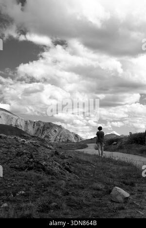 Caucasian female walking down a mountain path at Independence Pass in Colorado, USA, enjoying the alpine landscape. Stock Photo