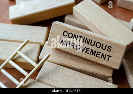 CONTINUOUS IMPROVEMENT text on wooden blocks on office desk representing ongoing process optimization and business efficiency. Stock Photo