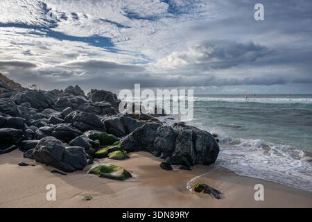 Rocky beach with dynamic waves under a cloudy, dramatic sky. Paia, Hawaii, USA Stock Photo