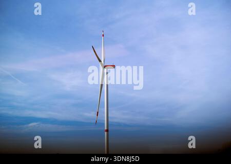 A single wind turbine stands against a vast clear blue sky with minimal cloud coverage. Germany Stock Photo