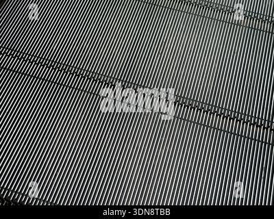 Detailed view of a contemporary escalator surface highlighting bright metallic ridges and dark grooves, emphasizing rhythm, linear design, and industr Stock Photo
