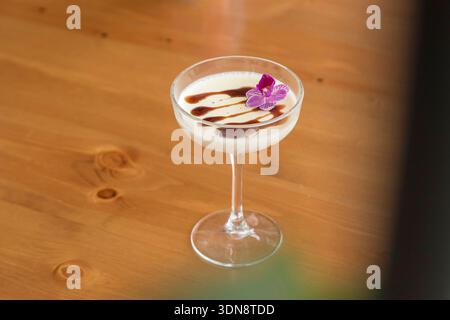 silky and creamy vanilla panna cotta served in an elegant glass goblet, beautifully topped with rich chocolate drizzle and a delicate purple edible fl Stock Photo