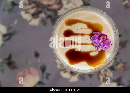 silky and creamy vanilla panna cotta served in an elegant glass goblet, beautifully topped with rich chocolate drizzle and a delicate purple edible fl Stock Photo
