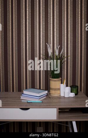 Modern home workspace with plant, books and striped wall background Stock Photo