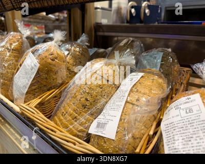 Poznan, Poland - November 28, 2025: Carrefour fresh pre-sliced whole grain bread, individually packaged in clear bags, fills wicker baskets, reflectin Stock Photo