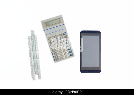 The macro shot captures a sleek calculator, a modern smartphone, and an antique slide rule positioned on a pristine white backdrop, highlighting the c Stock Photo